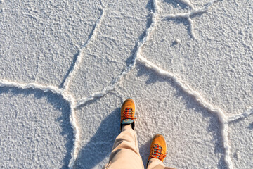 Obraz premium Salar de Uyuni, Bolivia. The tourist's feet stand on the salt surface.