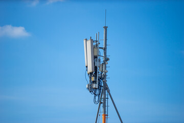 Telecommunication tower with blue sky and white clouds, technology background.