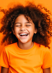 Cheerful african american little girl laughing on orange background