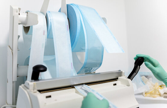 Photo of an unrecognizable dentist using a dental heat sealing machine to package dental instruments and other products.