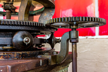 Mechanism of the searchlight of an old lighthouse tower in Guyana, South America. The copper or bronze or brass gears of the device rotate the huge spotlight lamp.World tourism, attractions.