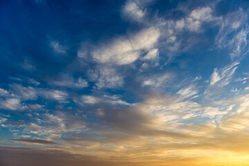 Cumulostratus, Stratus and Altocumulus clouds at golden hour in the blue sky lit by the sun at...