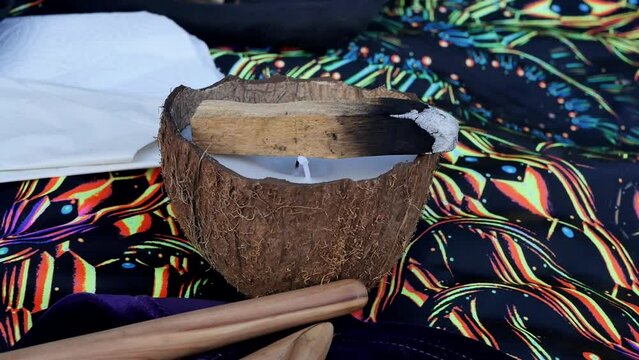 Close-up of a sacred Piruan tree smoldering with fire and smoke for fumigation during the shamanic rite of Rape. Palo Santo and a candle made of coconut on a blanket. Amazonian ancient practice