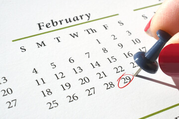 Marking Leap Year Day, February 29, on a calendar with a pushpin and red circle in ink - obrazy, fototapety, plakaty