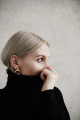 Portrait of a stylish woman in black sweater. Woman hiding her face with sweater's collar
