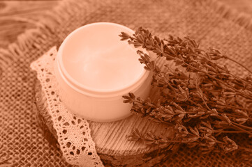 Peach fuzz is color of year 2024, tinted image. Organic lavender flowers, moisturizer cream on flaxen background. The concept of beauty and wellness. Skincare and body
