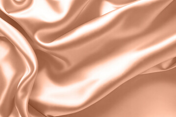 Fototapeta premium Abstract background, folds of silk fabric in peach fuzz color.