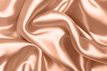 Abstract background, folds of silk fabric in peach fuzz color.