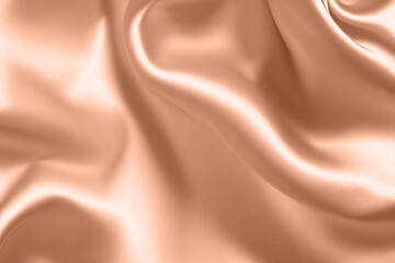 Fototapeta premium Abstract background, folds of silk fabric in peach fuzz color.