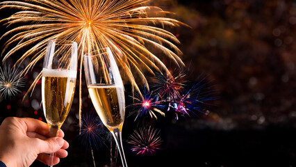 Brinde com ta&ccedil;a de champagne e decora&ccedil;&atilde;o dourada para celebra&ccedil;&atilde;o de ano novo e fogos de artificio ao fundo.