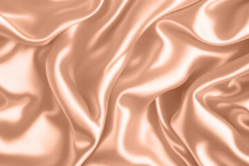 Abstract background, folds of silk fabric in peach fuzz color.