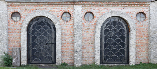 Very old solid door in brick stone wall of castle or fortress of 18th century. Full frame wall with...