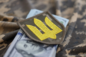 Ukrainian army symbol and bunch of dollar bills on military uniform. Payments to soldiers of the...