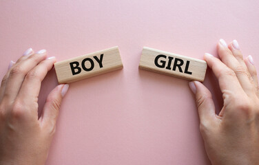 Boy or Girl symbol. Concept word Boy or Girl on wooden blocks. Man hand. Beautiful pink background. Gender and Boy or Girl concept. Copy space