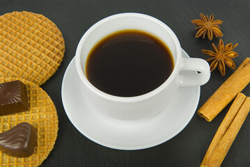 Cup of coffee, sweets and cinnamon on a black.
