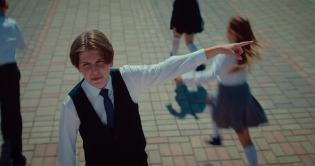 Portrait of schoolboy speaking and running with crowd of classmates in school yard, 4K, Prores