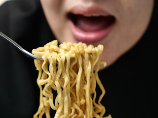 Asian muslim woman eating instant fried noodle, unhealthy food