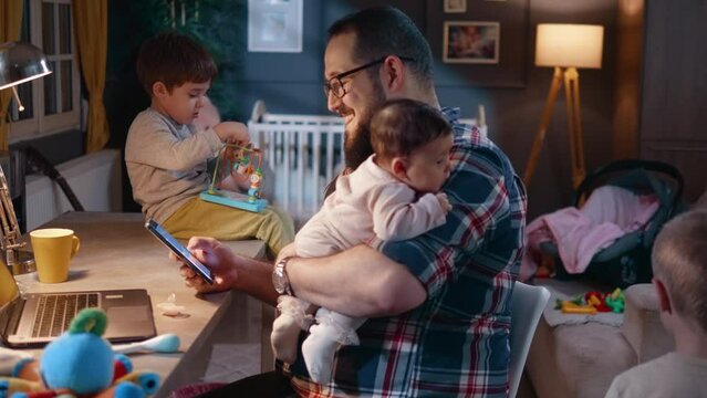 Happy single father at home at work desk with three kids