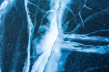 View from above on a natural blue cracked ice texture of surface of frozen Baikal Lake in cold snow winter day. Backdrop with copy space for advertising - obrazy, fototapety, plakaty