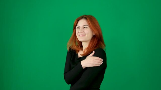 tenderness pleasant positive emotions hug yourself with your arms sway from side to side imagine dream visualize squint your eyes feel shy lower your eyelashes smile red-haired girl on green studio