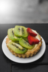 fruit tart with kiwi and strawberry on a flat plate, space for copying