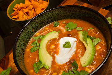 Hearty Chicken Enchilada Soup with Avocado and Sour Cream Garnish Close-Up