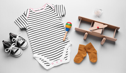 Baby clothes, accessories and toys on light background
