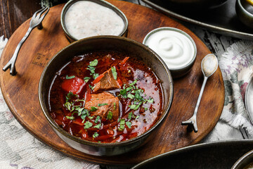 Ukrainian traditional beetroot soup - borscht in bowl with meat, rye bread and sour cream on bowl...