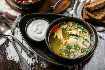 Chicken soup with meat, greens and sour cream on bowl on rustic wooden background. Healthy food,...