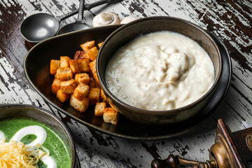 Mushroom cream soup with croutons in bowl on rustic wooden background. Healthy food, top view