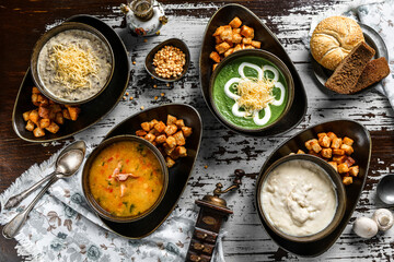 Vegetables soup with bacon, Mushroom cream soup and Vegan spinach soup on rustic wooden table. Healthy food, top view, flat lay