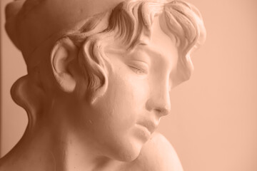 Close-up of a plaster bust of Sappho. Side view, place for text. Peach fuzz is color of year 2024.