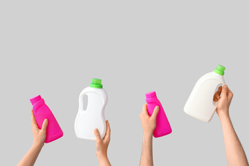 People with bottles of laundry detergent on light background