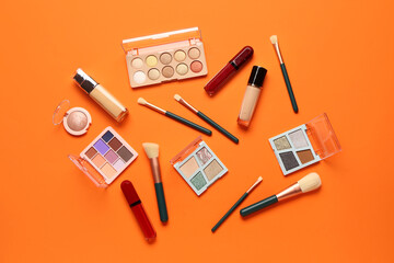 Beautiful palettes of eyeshadows and different decorative cosmetics on orange background - obrazy, fototapety, plakaty