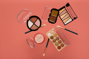 Beautiful palettes of eyeshadows and brushes on pink background