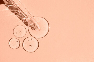 Transparent drops of hyaluronic acid and a glass pipette on a solid background. Top view, place for...