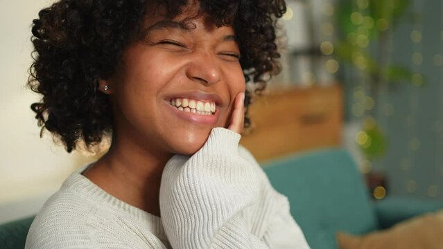 Beautiful African American girl with afro hairstyle smiling. Close up portrait of young happy black girl. Young African woman with curly hair laughing. Freedom happiness carefree happy people concept