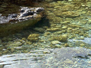 Sea crystal clear water with stones pebbles gravel sand at the bottom.