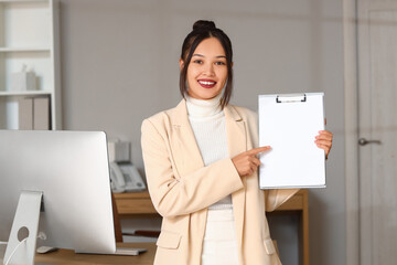 Young Asian businesswoman with clipboard in office