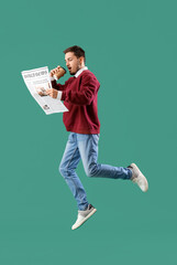 Young man with newspaper and coffee cup jumping on green background