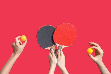 Female hands with ping pong rackets and balls on red background