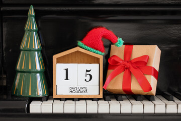 Calendar with text 15 DAYS UNTIL HOLIDAYS, Christmas gift and decor on piano keys