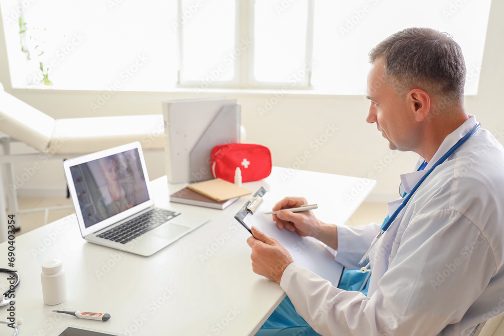 Sticker Mature doctor video chatting with patient on laptop in office