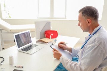Mature doctor video chatting with patient on laptop in office