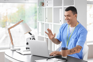 Obraz premium Male doctor video chatting at desk in clinic