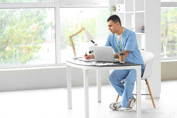 Male doctor working at desk in clinic
