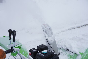 A man cleans snow in the winter in the courtyard of the house,  man cleaning snow with a snow blower