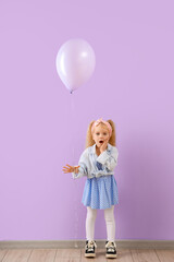 Cute shocked little girl with beautiful balloon near purple wall