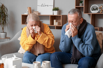Sick mature couple with tissues sitting at home - obrazy, fototapety, plakaty