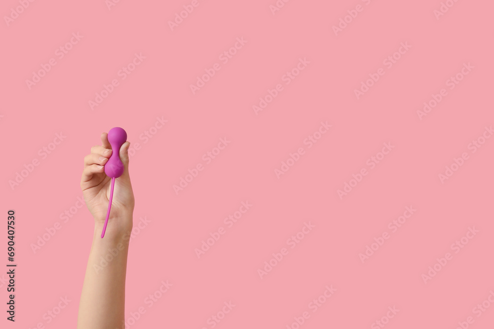 Wall mural Female hand with vaginal balls on pink background